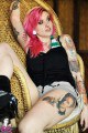 Pink haired babe with tattoos sitting on the chair 