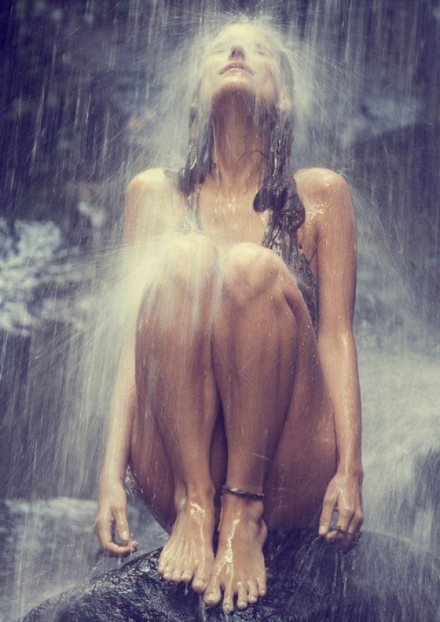 Erotic babe sits under the waterfall