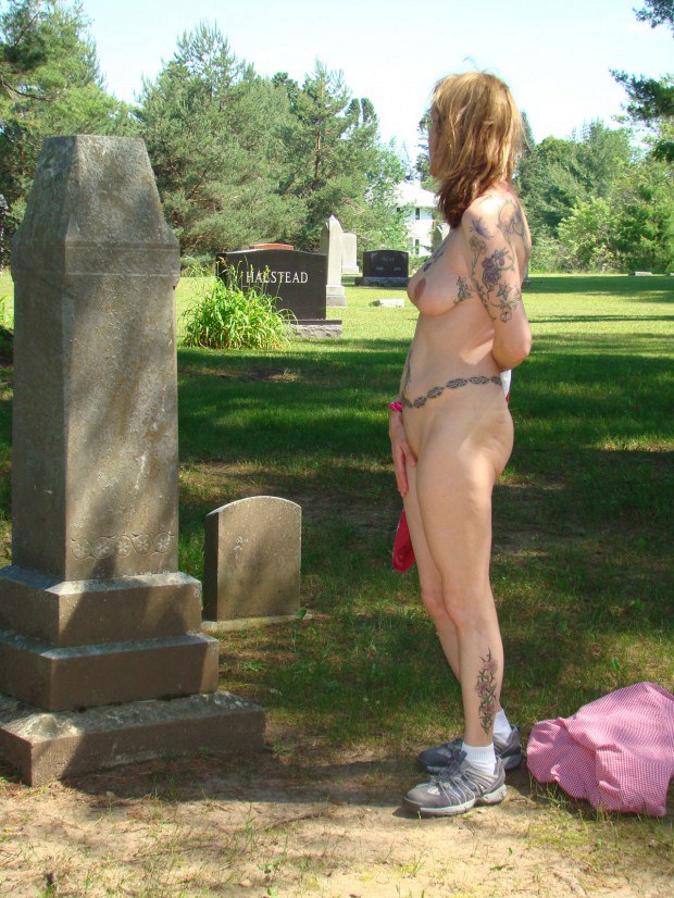 Inked exhibitionist is naked in a cemetery