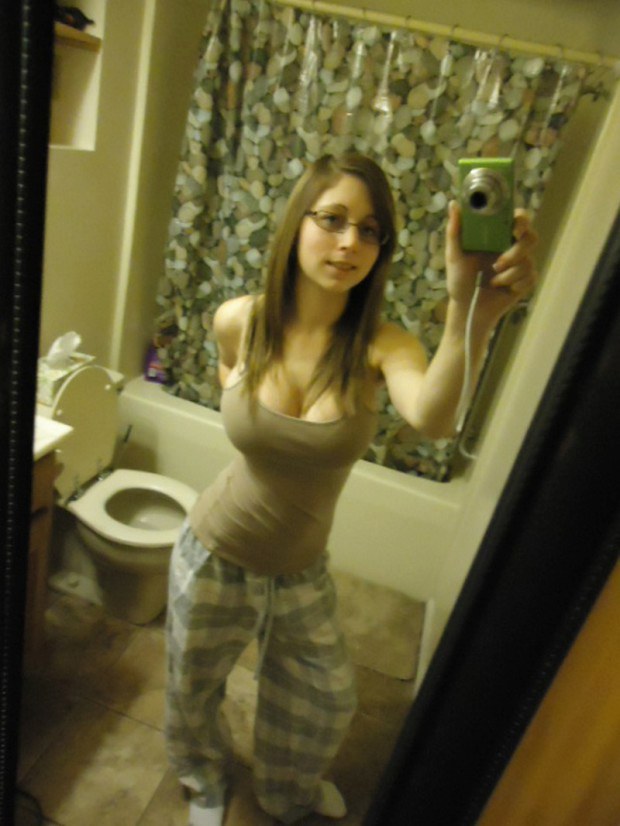 Busty teen with glasses takes a selfie in the bathroom